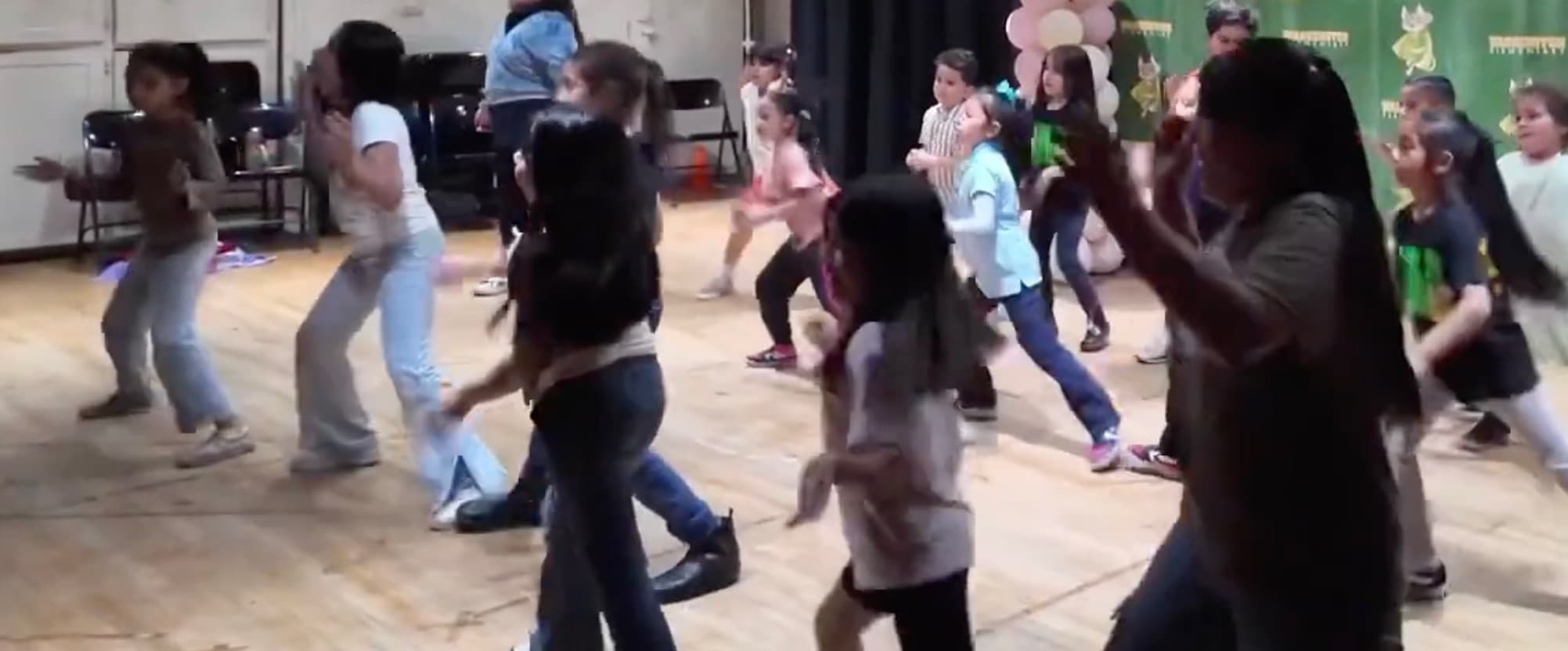 A large group of students dancing together on stage during an iAttend Dance program.